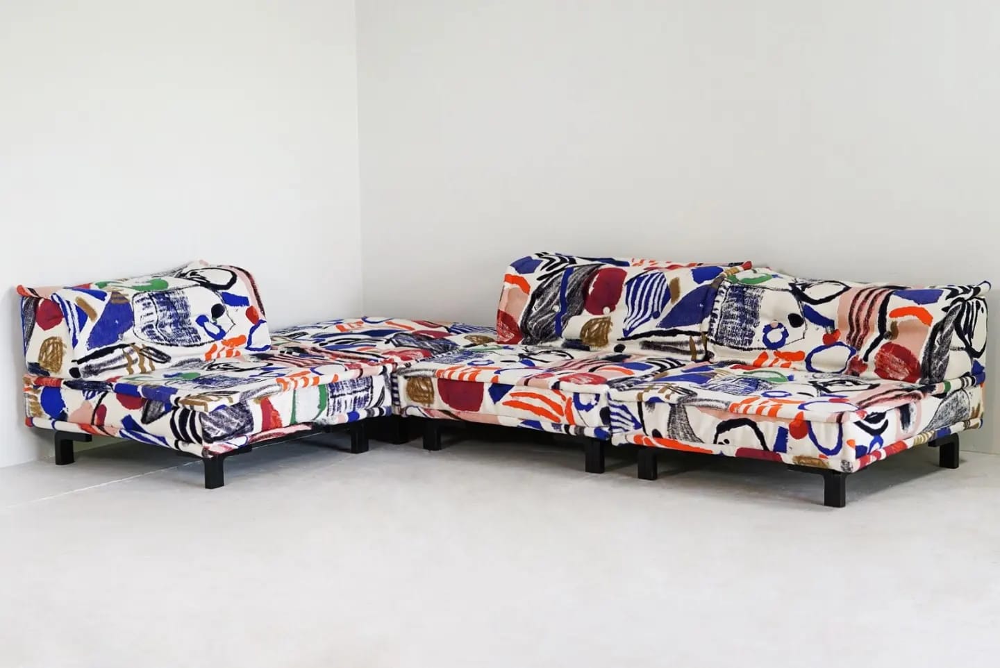 Een L sofa met kleurrijk patroon van blauw, rood en wit