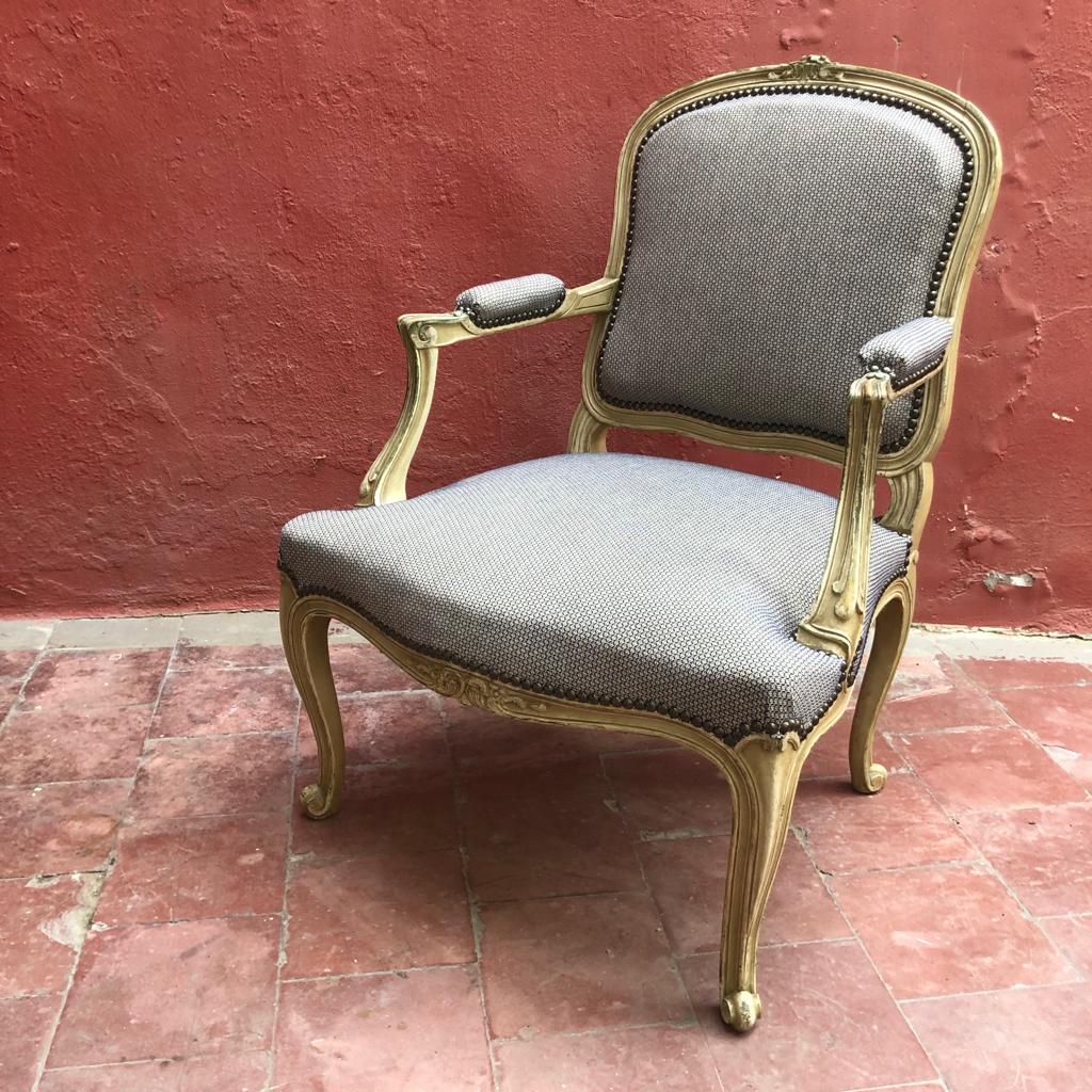 Een stoel met grijze kussens voor een rode muur